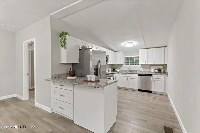 a kitchen with cabinets stainless steel appliances and a window