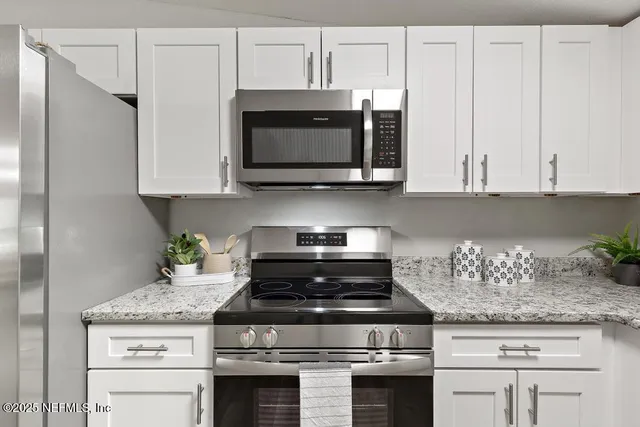 a kitchen with stainless steel appliances white cabinets and a stove top oven