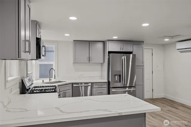 a kitchen with stainless steel appliances kitchen island granite countertop a refrigerator a stove and a sink with wooden floor