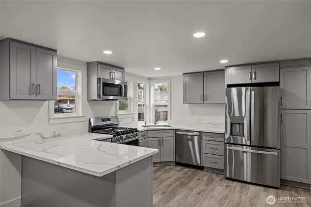 a kitchen with a sink a stainless steel refrigerator and cabinets