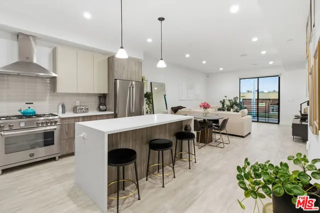 a kitchen with stainless steel appliances kitchen island granite countertop a table chairs sink and cabinets