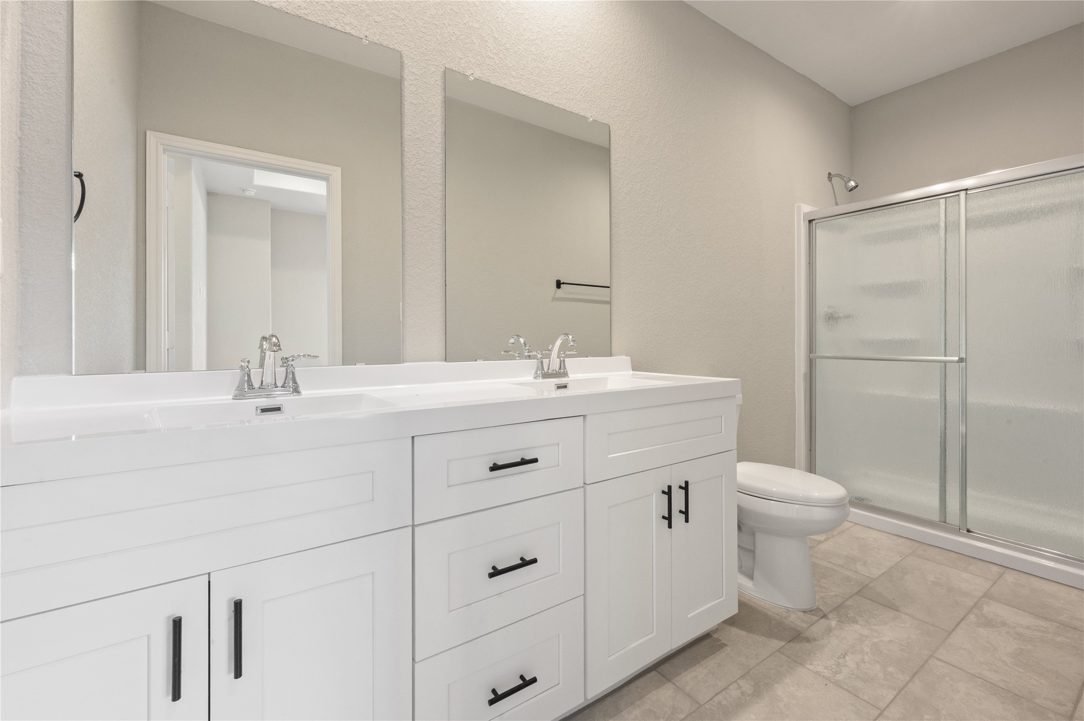 14010 Longstreet Road, Unit 2 Willis, TX 77318 - Photo 14 of 29 This bathroom features a modern design with a double vanity, sleek white cabinetry, and a spacious shower with sliding glass doors. Neutral tile flooring and soft lighting create a clean and inviting atmosphere.