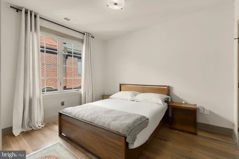 a bed sitting in a bedroom next to a window and wooden floor