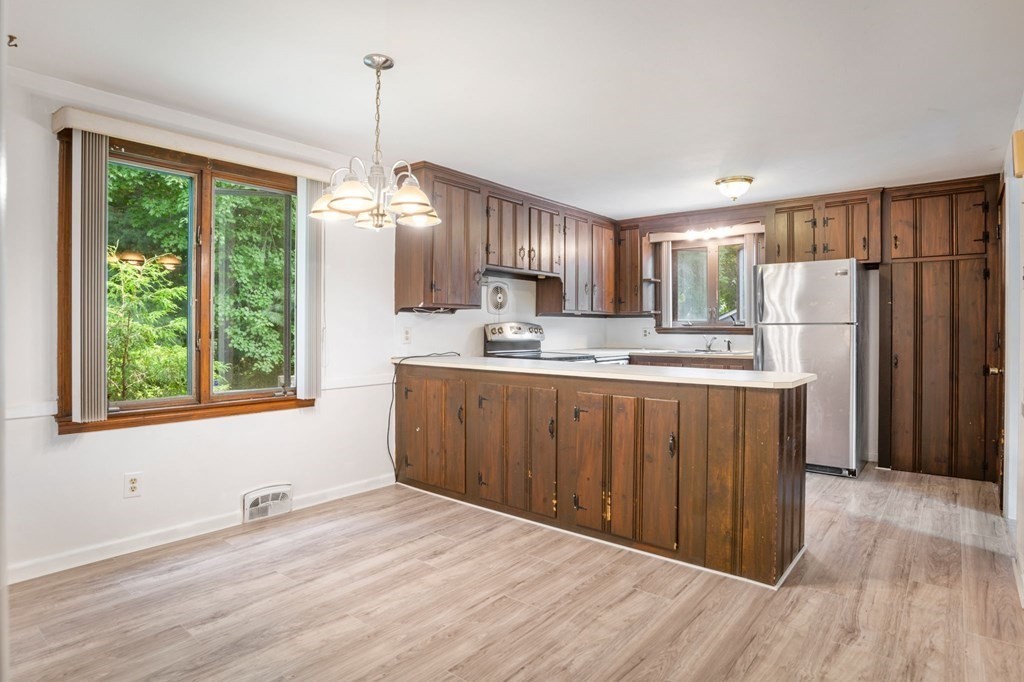23 Plumtree Circle Springfield, MA 01118 - Photo 18 of 29 a kitchen with stainless steel appliances granite countertop a refrigerator a sink dishwasher a stove and a dining table with wooden floor