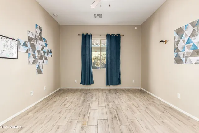 a view of an empty room with window and hardwood floor