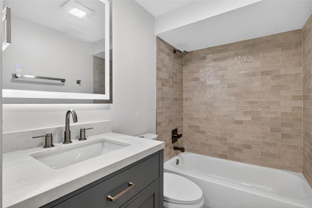 9826 Pocono Street Port Richey, FL 34668 - Photo 14 of 15 a bathroom with a granite countertop sink a toilet and bathtub