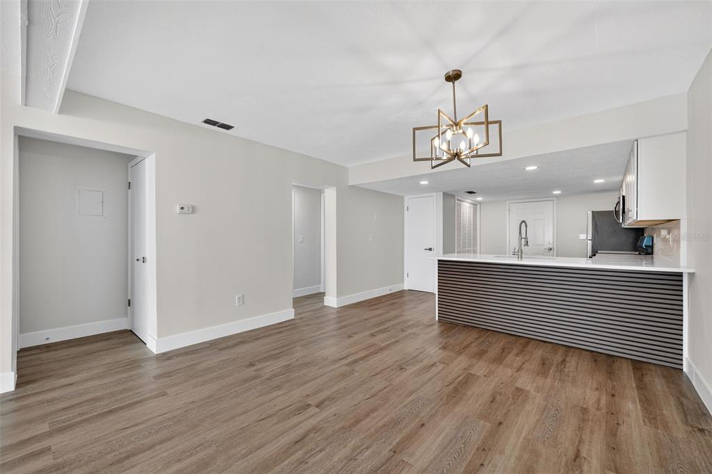 9826 Pocono Street Port Richey, FL 34668 - Photo 4 of 15 a view of a room with wooden floor kitchen cabinets and chandelier