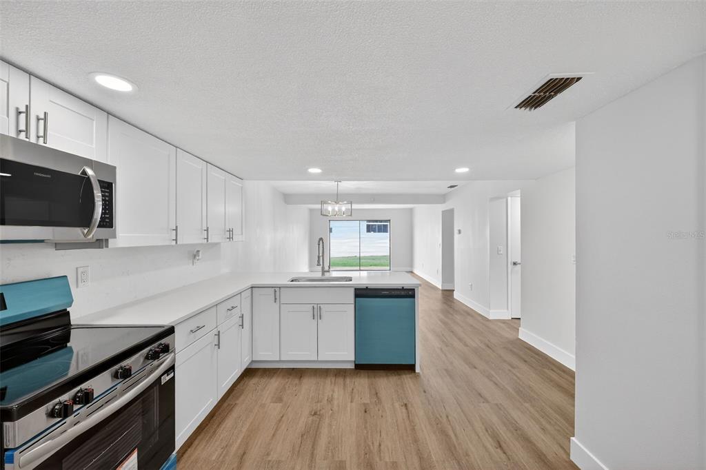 9826 Pocono Street Port Richey, FL 34668 - Photo 6 of 15 a kitchen with stainless steel appliances kitchen island granite countertop a sink cabinets and wooden floor