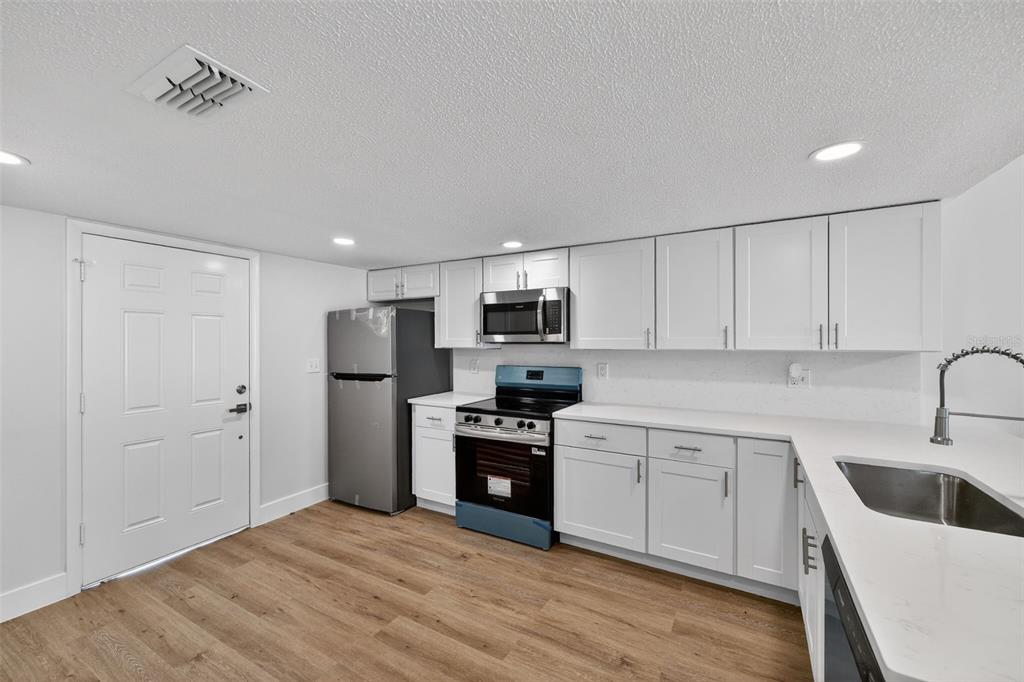 9826 Pocono Street Port Richey, FL 34668 - Photo 8 of 15 a kitchen with white cabinets and stainless steel appliances