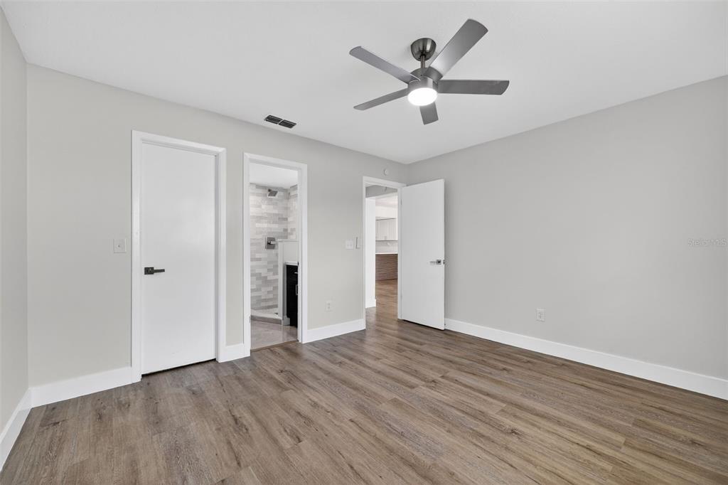 9826 Pocono Street Port Richey, FL 34668 - Photo 9 of 15 an empty room with wooden floor and a ceiling fan