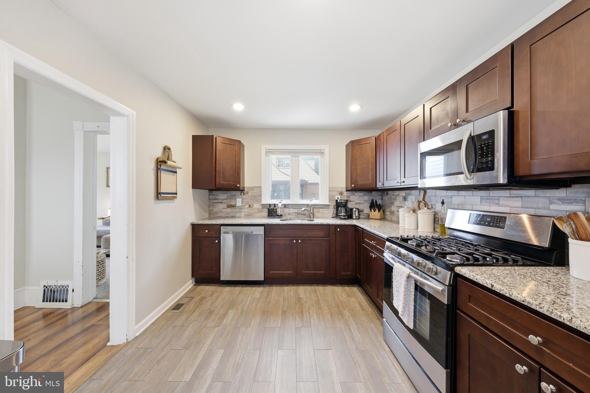 212 Grape Street Hammonton, NJ 08037 - Photo 17 of 36 a kitchen with stainless steel appliances granite countertop a stove top oven a sink dishwasher a refrigerator and a microwave oven with wooden floor