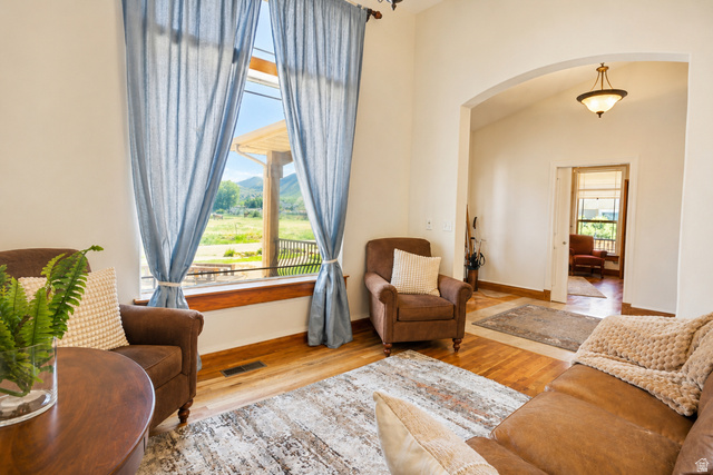 1055 North 1000 East Mapleton, UT 84664 - Photo 5 of 112 Living area featuring a large picture window with mountain scenery, wood-finish flooring, a vaulted ceiling, an arched entryway, and a semi-flush mount ceiling light fixture