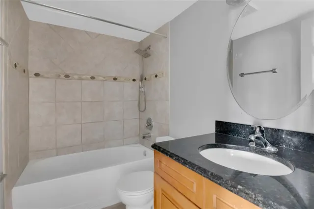 a bathroom with a granite countertop sink a mirror a bathtub and shower