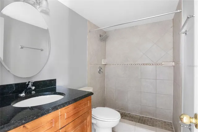 a bathroom with a granite countertop sink toilet a mirror a vanity and shower
