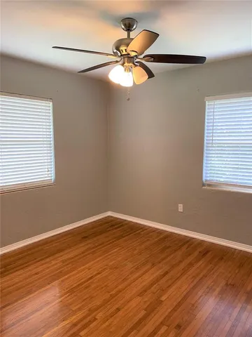 a view of a room with wooden floor and a ceiling fan