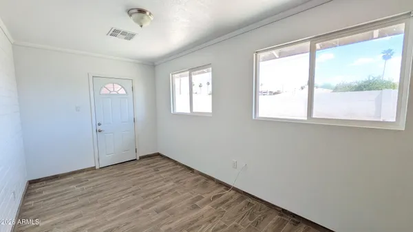 a view of an empty room with wooden floor and a window