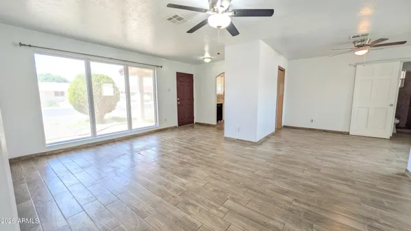 a view of an empty room with a window and wooden floor