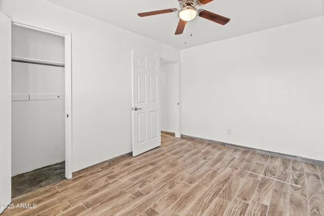 an empty room with a hardwood and ceiling fan