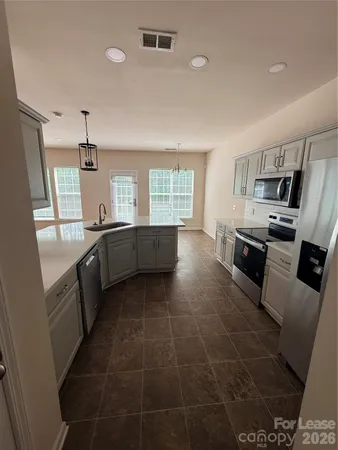 a large kitchen with stainless steel appliances granite countertop a sink and dishwasher a stove top oven with wooden floor