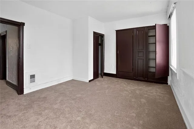 a view of an empty room with closet and cabinet