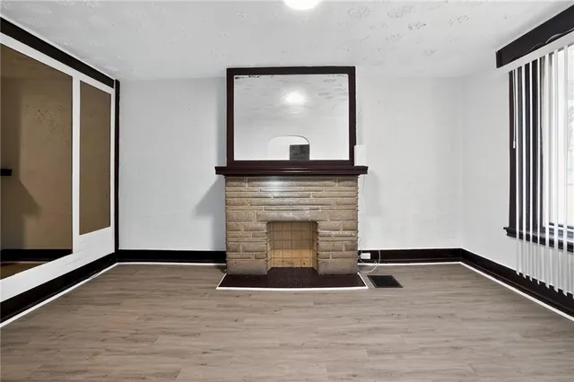 a view of empty room with wooden floor and fireplace