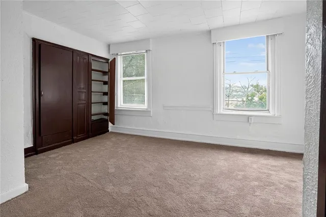 an empty room with windows closet and chandelier fan