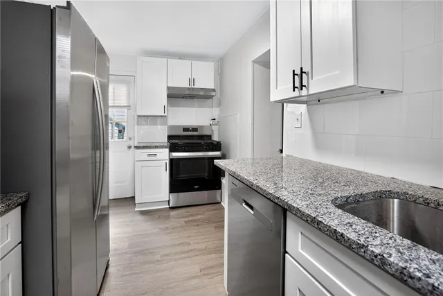 a kitchen with stainless steel appliances granite countertop a sink a stove a refrigerator and cabinets