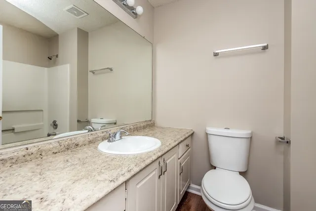 a bathroom with a granite countertop sink a toilet and a mirror