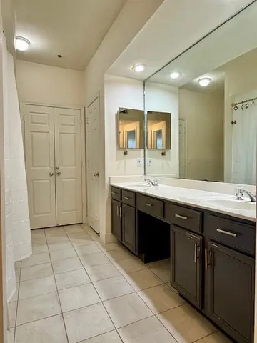 a spacious bathroom with a double vanity sink a mirror and a bathtub