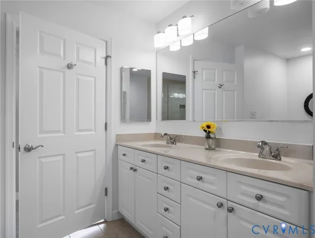 a bathroom with double vanity sinks a vanity a lamp and a mirror