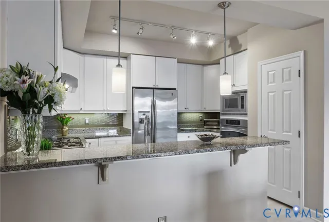 a kitchen with stainless steel appliances a refrigerator a sink a stove and chairs