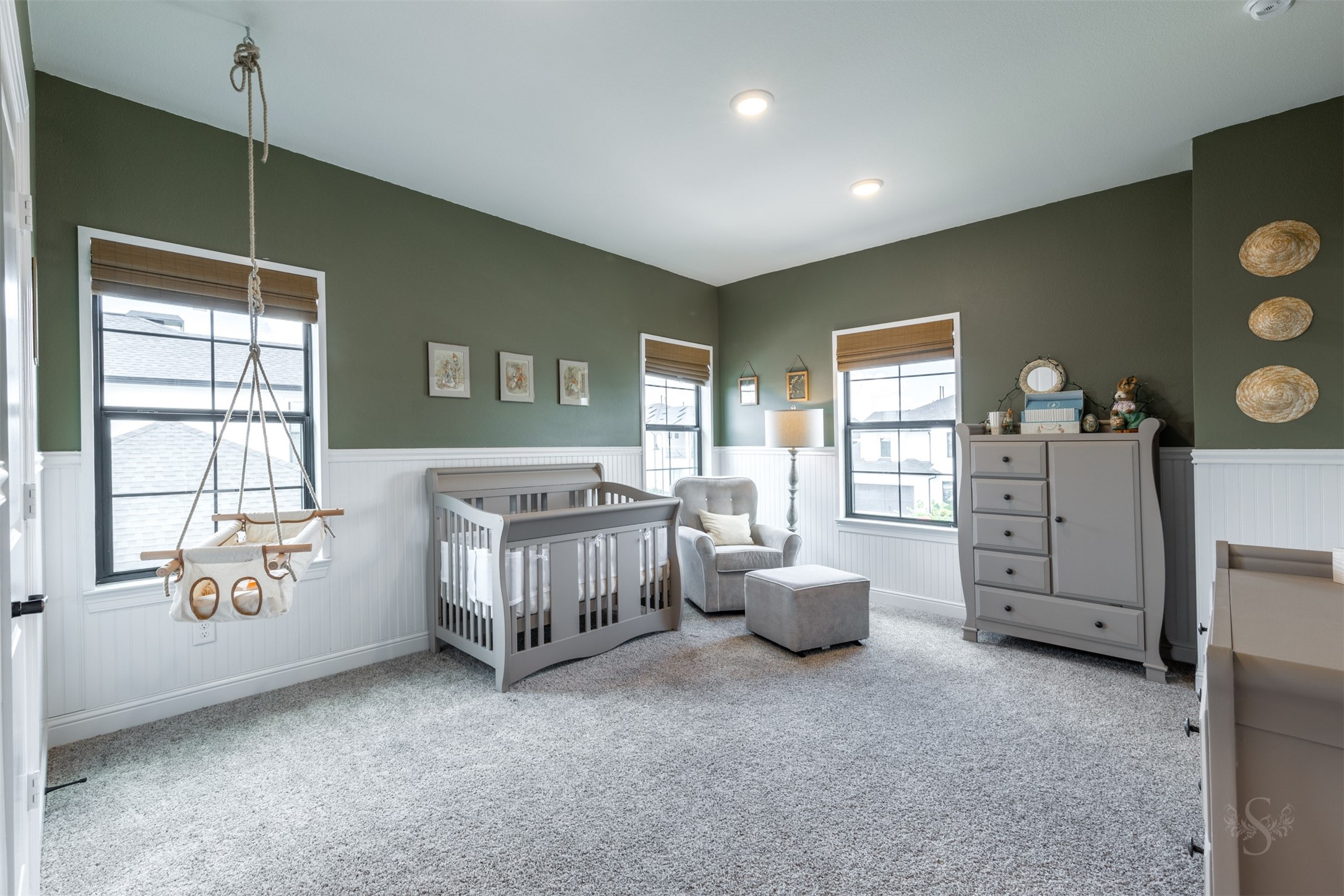 27919 Indigo Ridge Drive Fulshear, TX 77441 - Photo 38 of 50 This inviting secondary bedroom showcases elegant wainscoting, warm green accents, and multiple windows that fill the room with soft, natural light. Its generous layout offers a comfortable and serene setting for guests or family members.