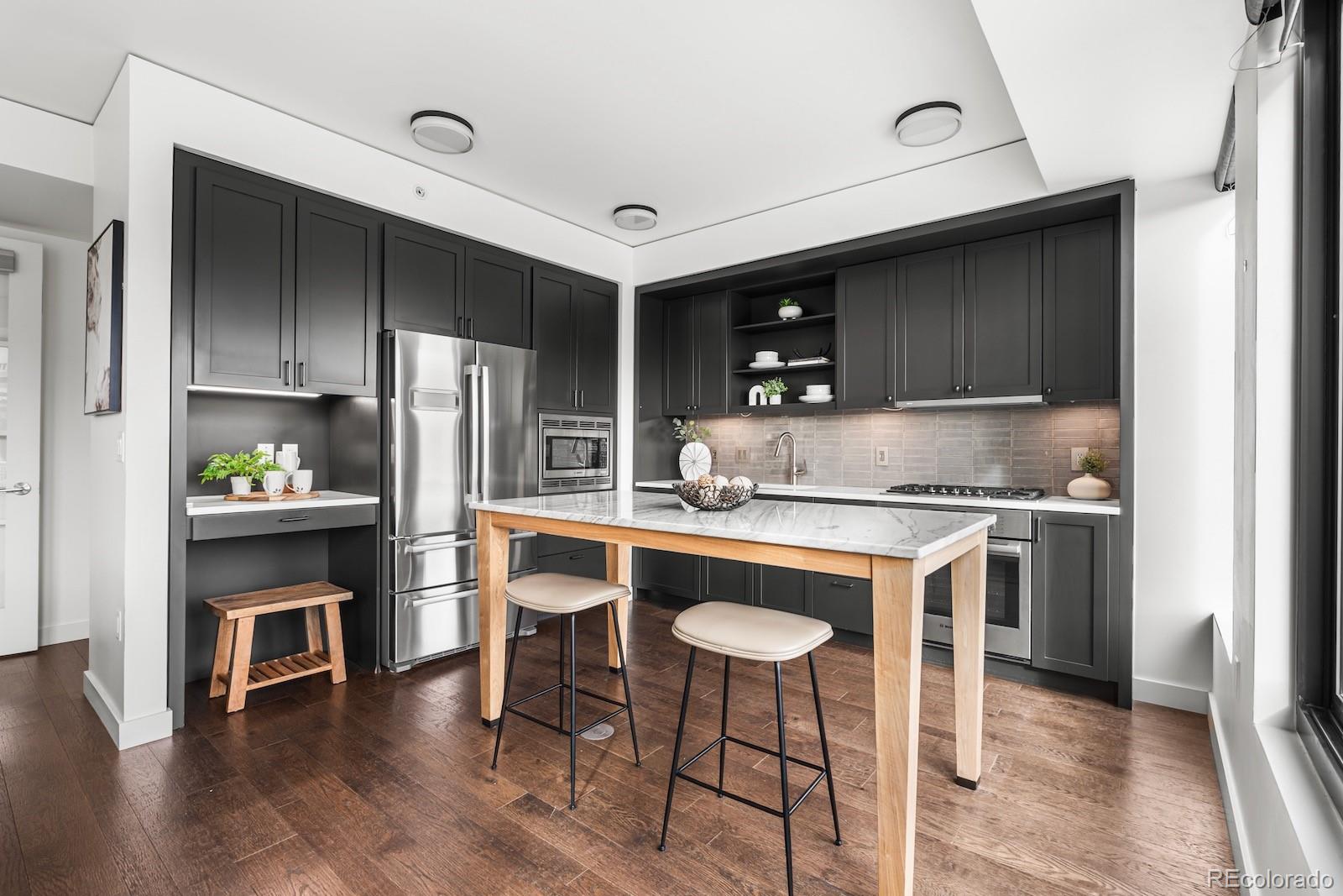 1750 Wewatta Street, Unit 1030 Denver, CO 80202 - Photo 4 of 50 a kitchen with kitchen island granite countertop a sink cabinets and stainless steel appliances