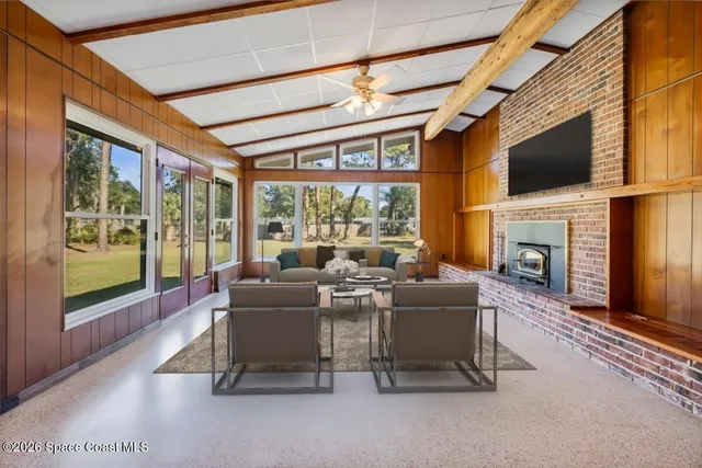a view of a hall with wooden floor and a fireplace