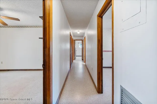 an empty room with windows and chandelier fan