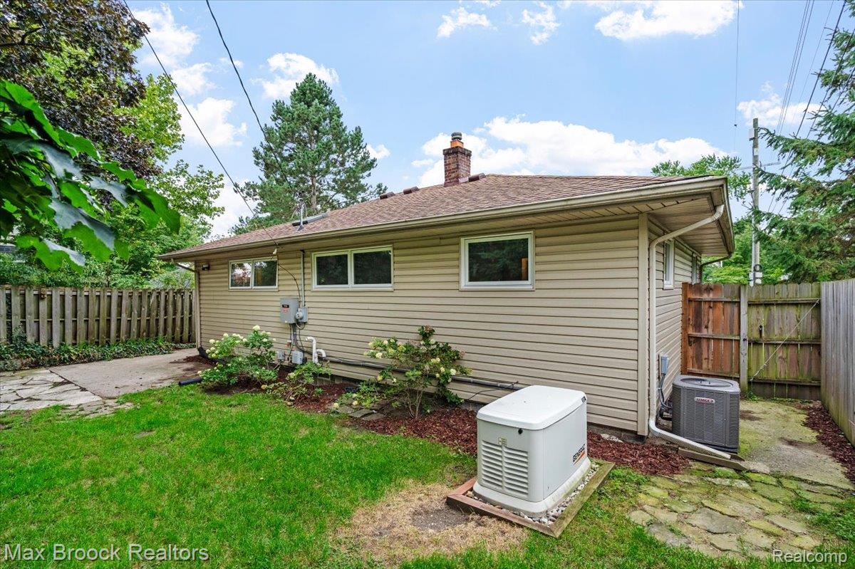 1330 Oak Street Rochester, MI 48307 - Photo 25 of 35 Exterior featuring neutral siding, multiple windows, a paved walkway, a gravel patio area, and a fenced perimeter