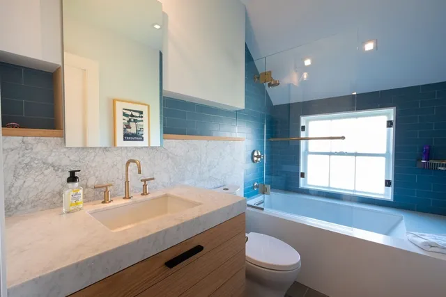 a bathroom with a sink a toilet a window and mirror