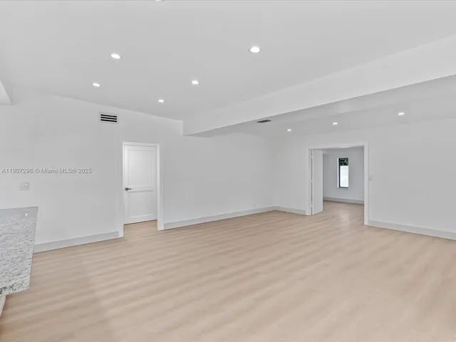 a view of an empty room with window and wooden floor