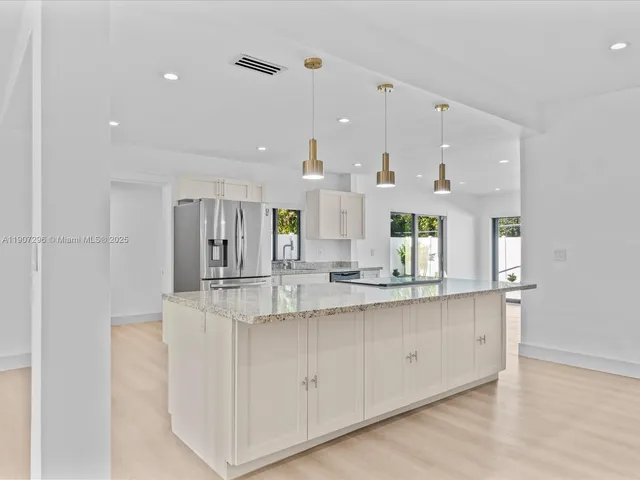 a kitchen with kitchen island white cabinets and refrigerator