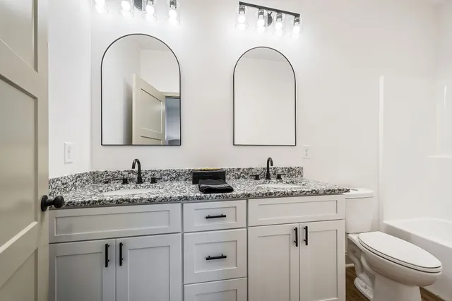 a bathroom with a granite countertop sink a toilet and mirror