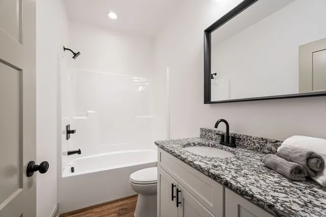 a bathroom with a granite countertop sink a toilet and shower