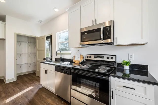 a kitchen with stainless steel appliances granite countertop a stove a microwave and a white cabinets