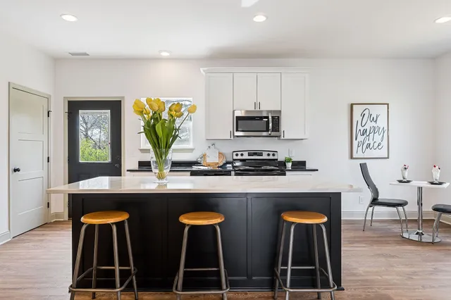 a kitchen with stainless steel appliances a dining table chairs refrigerator and sink