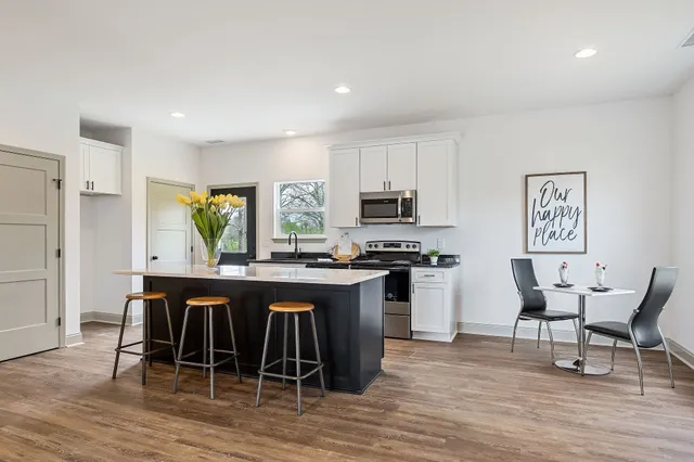 a kitchen with stainless steel appliances a dining table chairs and wooden floor