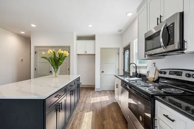 a kitchen with stainless steel appliances granite countertop a stove a sink and a microwave