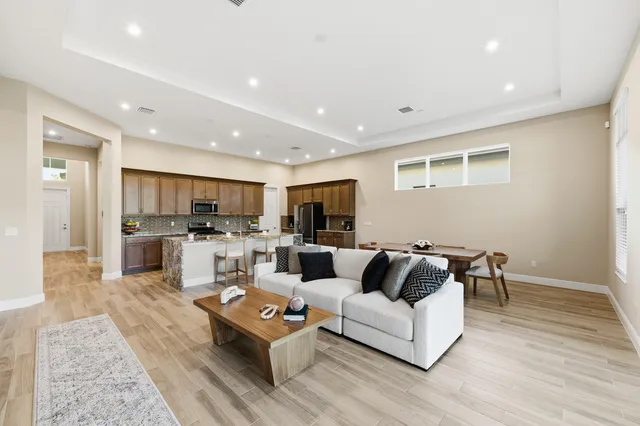 a living room with furniture kitchen view and a wooden floor
