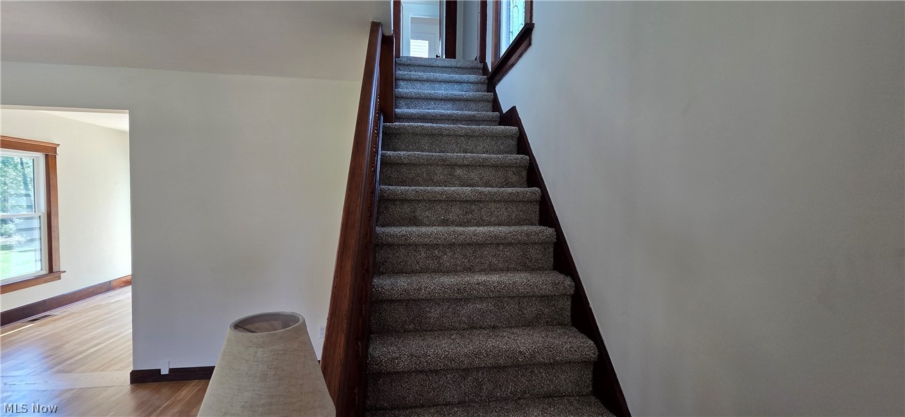 9964 East River Road Elyria, OH 44035 - Photo 20 of 45 Staircase with carpeted treads and a dark wood-finish handrail