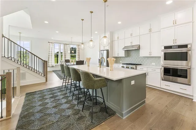 a kitchen with stainless steel appliances granite countertop a table chairs stove and a sink