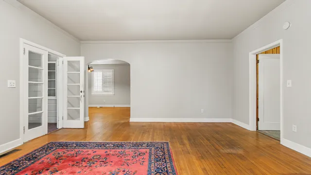 a view of an empty room with wooden floor and window