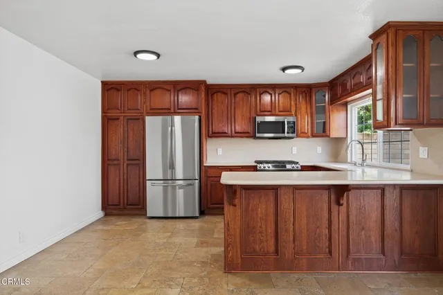 a kitchen with stainless steel appliances granite countertop a refrigerator a stove a sink and a microwave